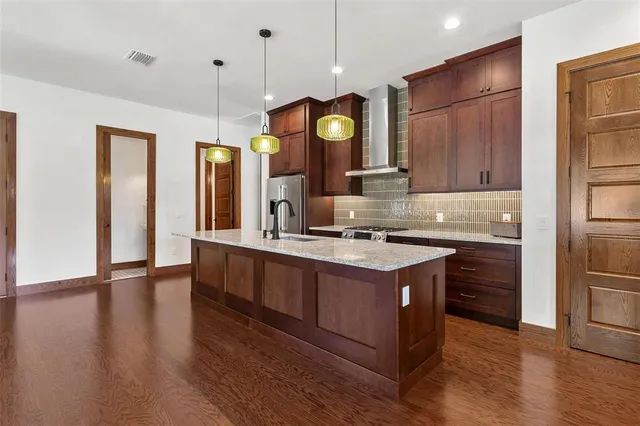 a kitchen with stainless steel appliances granite countertop a sink a stove and a wooden floors
