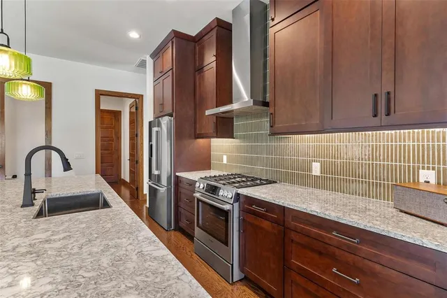 a kitchen with granite countertop a stove a sink and a refrigerator
