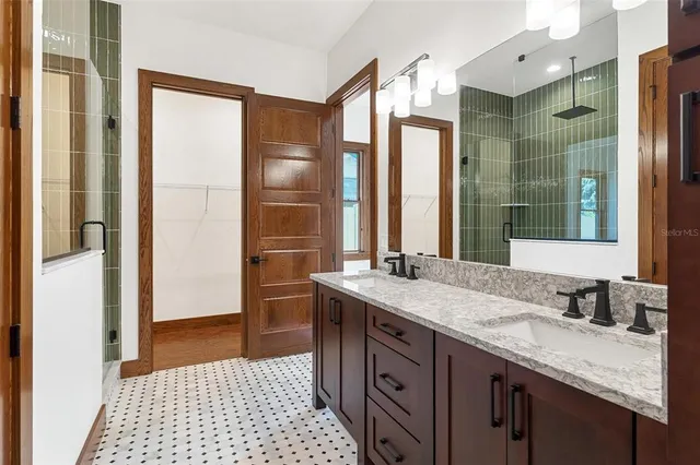 a bathroom with a granite countertop sink a mirror and a shower