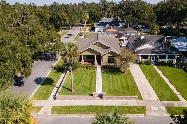 an aerial view of a house with swimming pool and large trees