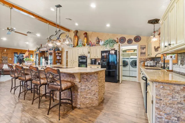 a kitchen with stainless steel appliances kitchen island granite countertop a table and chairs with wooden floor