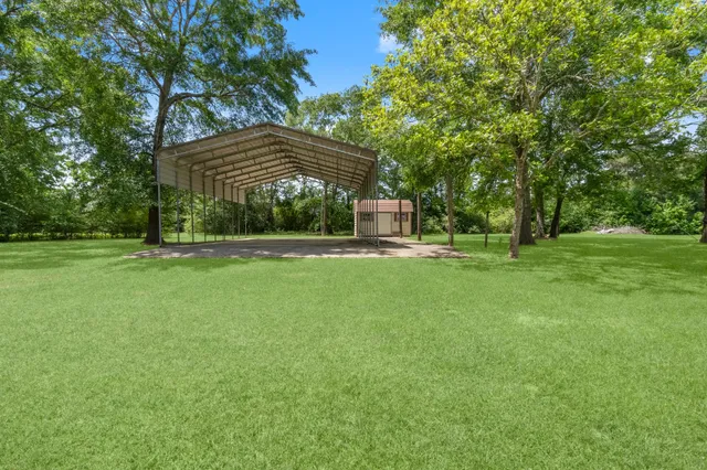 an aerial view of residential house with outdoor space and trees all around