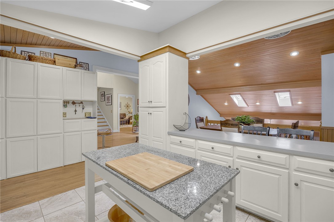 218 Northridge Drive Anderson, SC 29621 - Photo 11 of 50 A well-appointed kitchen features ample white cabinetry, granite island, and views into a lofty, wood-paneled living area with skylights.