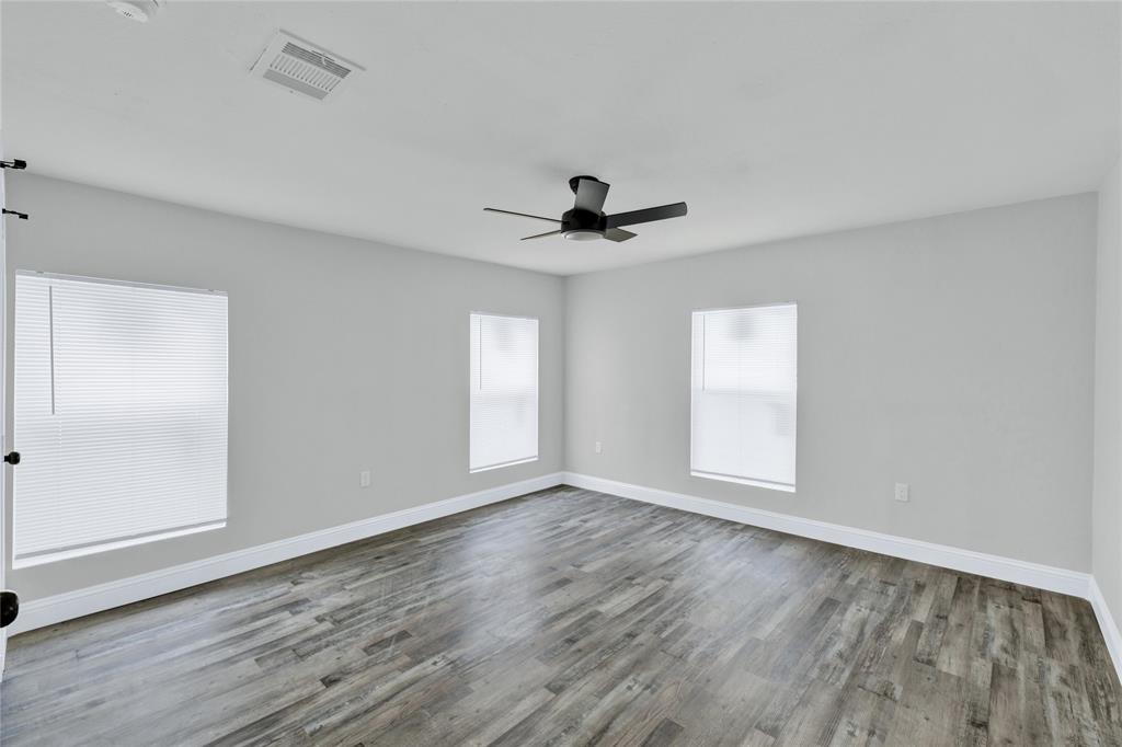 501 North Miller Street Decatur, TX 76234 - Photo 17 of 24 Spacious room featuring wood-finish flooring, light gray walls, multiple windows, and a ceiling fan