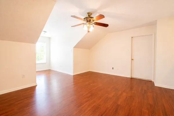 a view of a room with wooden floor and a ceiling fan