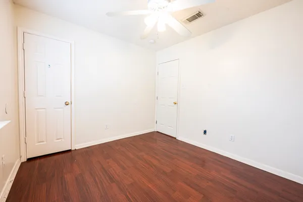 an empty room with wooden floor and white walls
