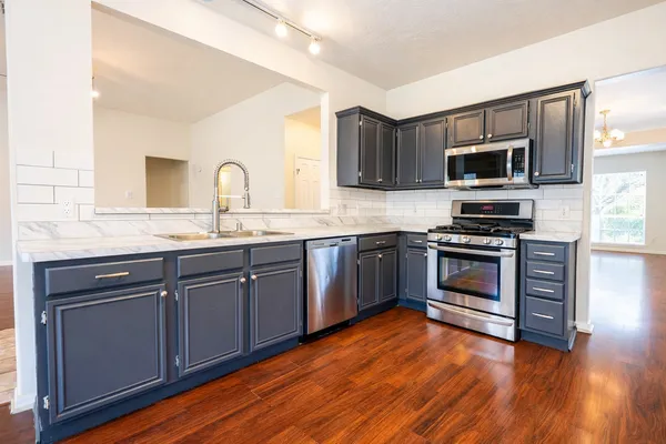 a kitchen with stainless steel appliances granite countertop a stove top oven and sink