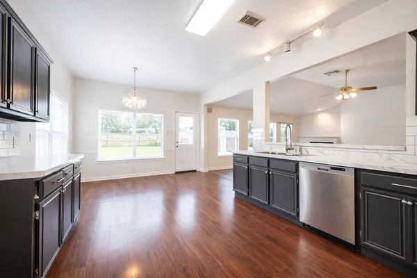 a kitchen with stainless steel appliances granite countertop wooden floors and wide window