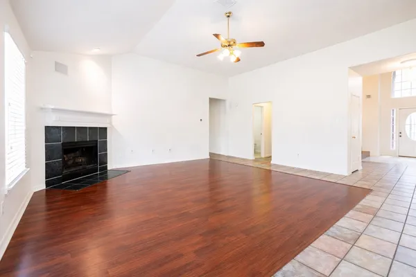 an empty room with wooden floor fireplace and window