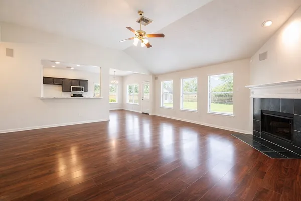an empty room with wooden floor fireplace and windows