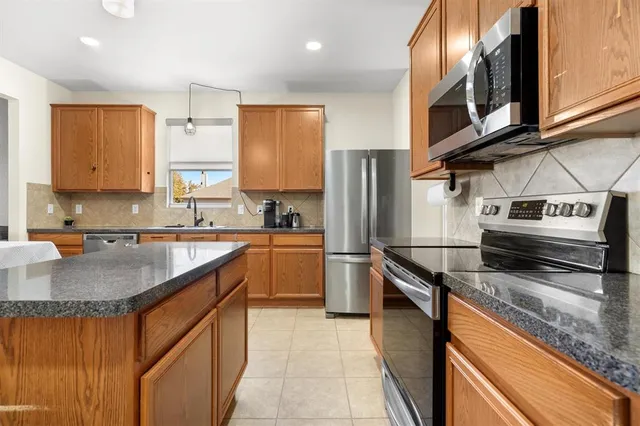 a kitchen with stainless steel appliances granite countertop a stove a sink and a refrigerator