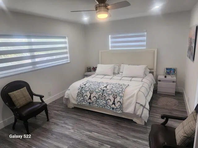 a bedroom with a bed chair and two windows