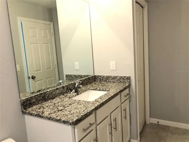 a bathroom with a granite countertop sink and a mirror