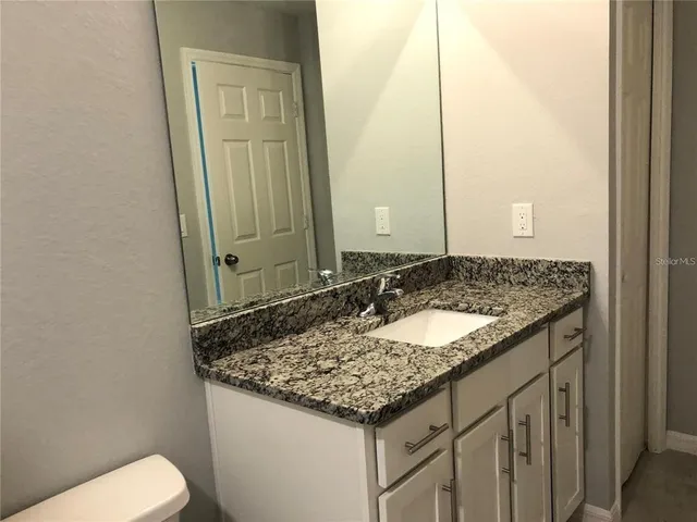 a bathroom with a granite countertop sink and a mirror