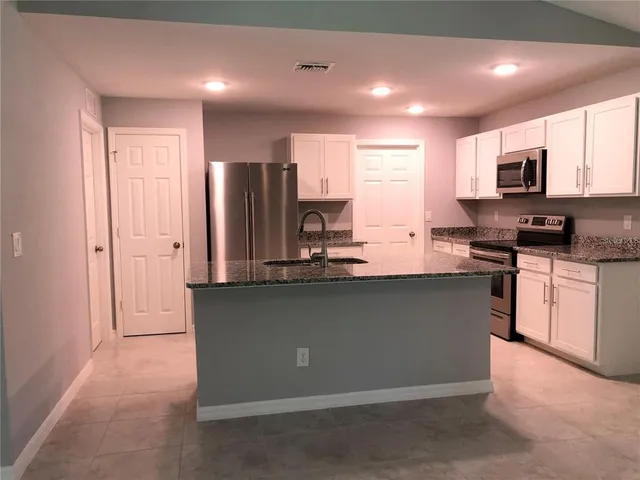 a kitchen with stainless steel appliances granite countertop a stove a sink and a refrigerator