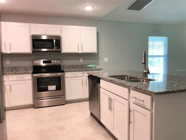 a kitchen with granite countertop a stove and a sink