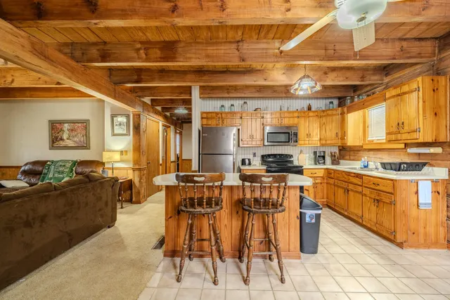 a open kitchen with stainless steel appliances kitchen island granite countertop a table and chairs in it