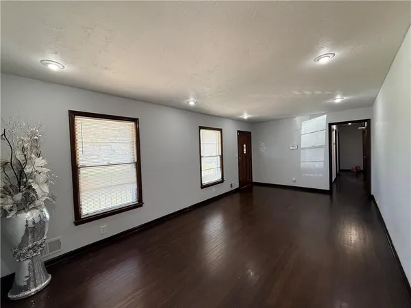a view of an empty room with a window and wooden floor