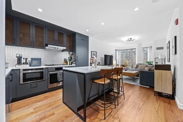 a kitchen with stainless steel appliances kitchen island granite countertop a table chairs and a refrigerator