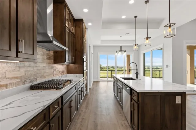 a kitchen with stainless steel appliances granite countertop a stove a sink dishwasher and a refrigerator with wooden floor