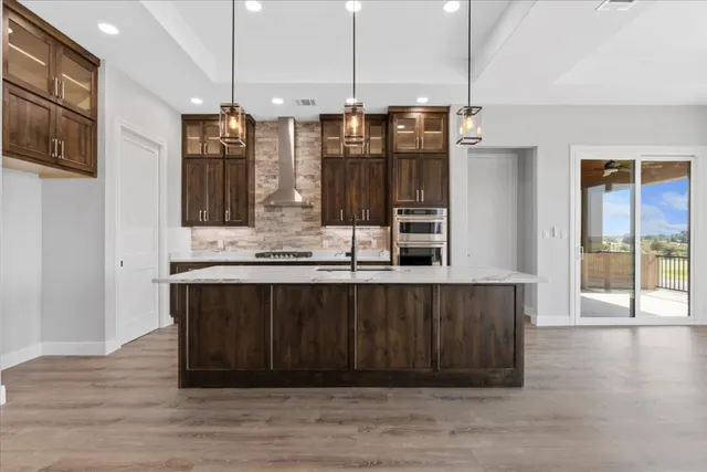 a kitchen with stainless steel appliances granite countertop a sink a stove and a wooden floors