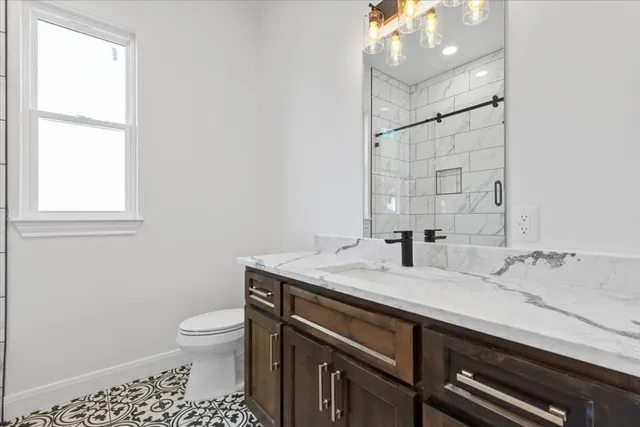 a bathroom with a granite countertop sink a toilet and a mirror