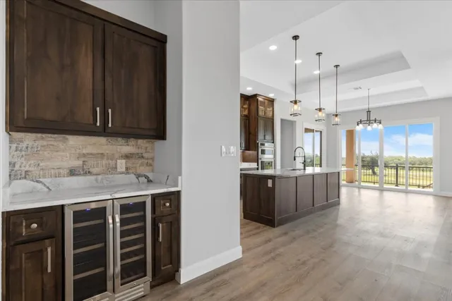 a kitchen with stainless steel appliances kitchen island granite countertop a refrigerator a sink dishwasher and wooden cabinets with wooden floor