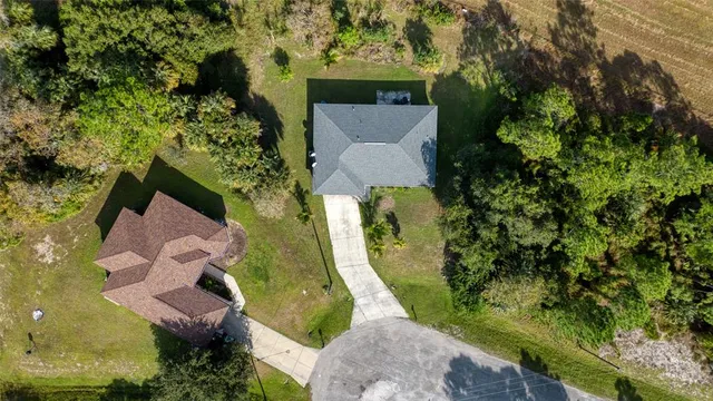 an aerial view of a house with a yard and large trees