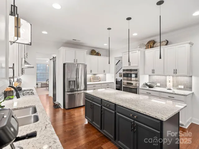 a kitchen with stainless steel appliances granite countertop a sink a stove and a refrigerator