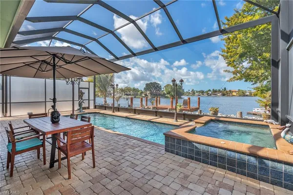 a view of a swimming pool with a table and chairs under an umbrella