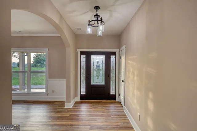 a view of a hallway with wooden floor and a chandelier