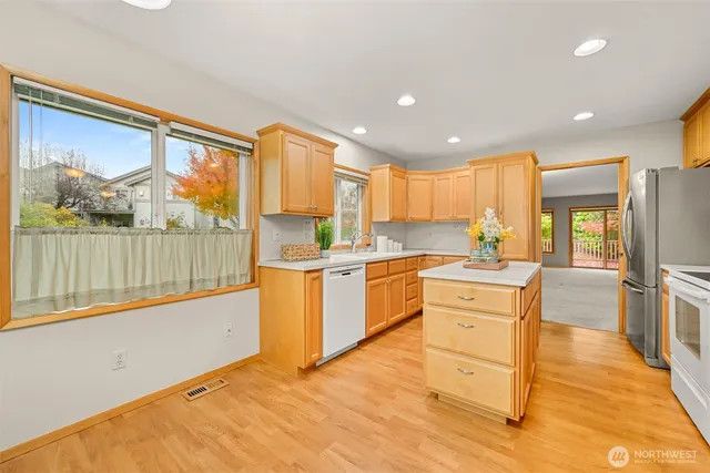 a kitchen with stainless steel appliances kitchen island granite countertop a refrigerator a stove top oven and white cabinets