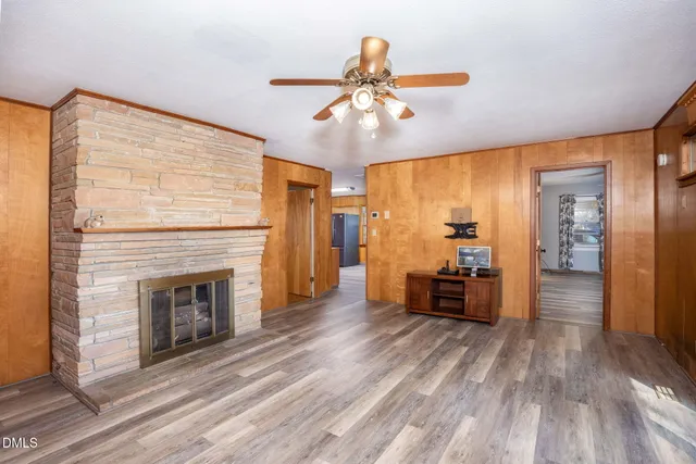 a view of a livingroom with a fireplace wooden floor and chandelier fan