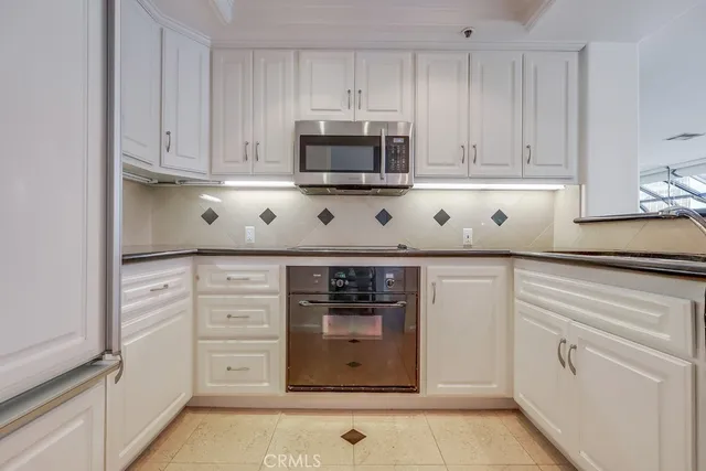 a kitchen with white cabinets and appliances