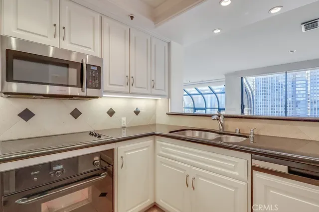 a kitchen with granite countertop white cabinets stainless steel appliances and a sink