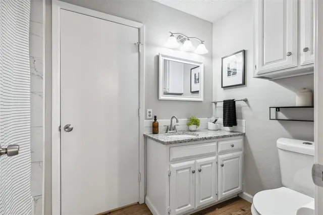 a bathroom with a granite countertop toilet sink and mirror