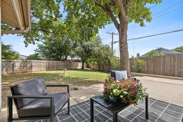 a backyard with table and chairs potted plants and a large tree