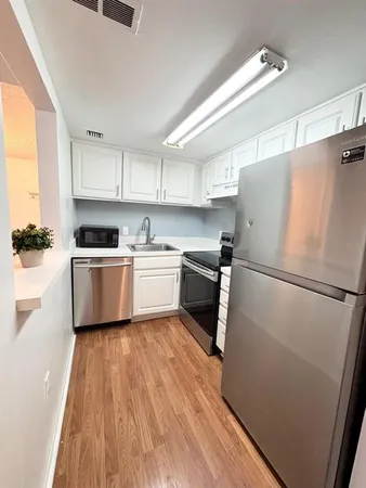 a kitchen with a refrigerator a sink and white cabinets