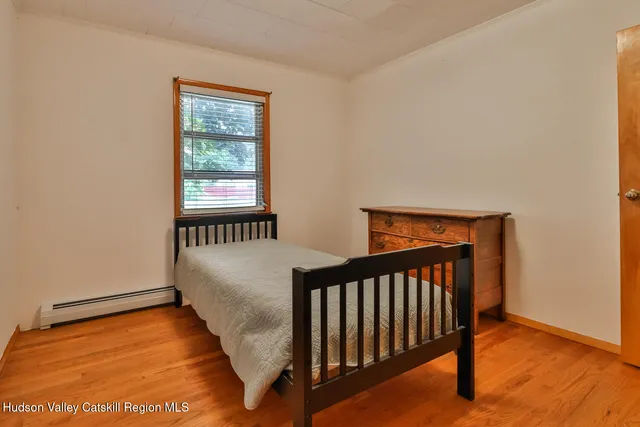 a bedroom with a bed wooden floor and window