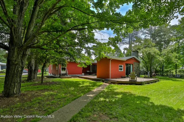a front view of a house with a yard garden and trees