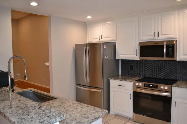 a kitchen with stainless steel appliances granite countertop a refrigerator and a stove top oven