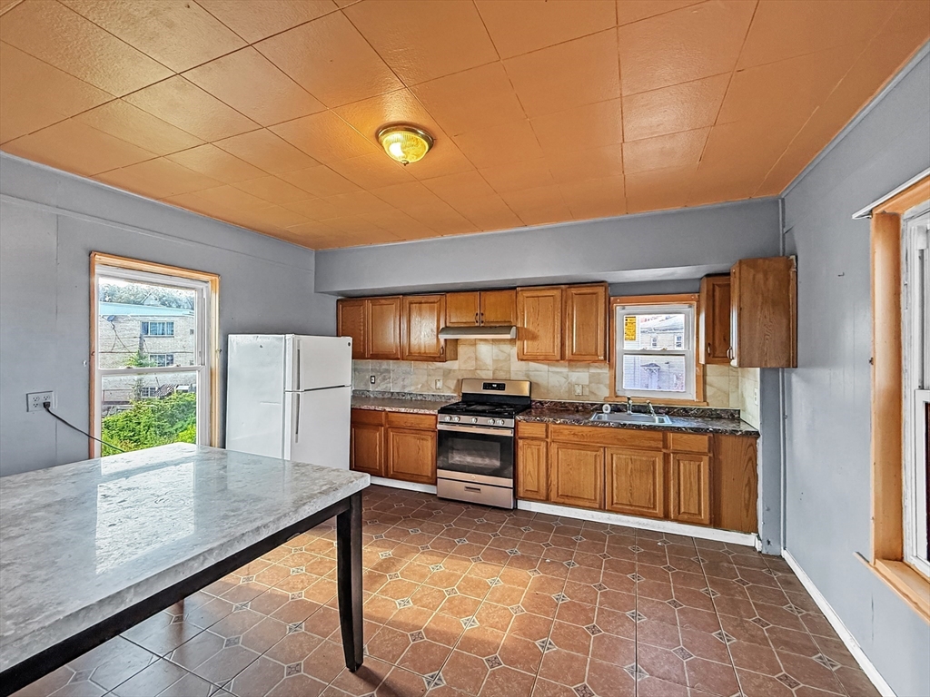 19 High Street Lynn, MA 01902 - Photo 20 of 42 a kitchen with stainless steel appliances granite countertop a stove a sink and a refrigerator