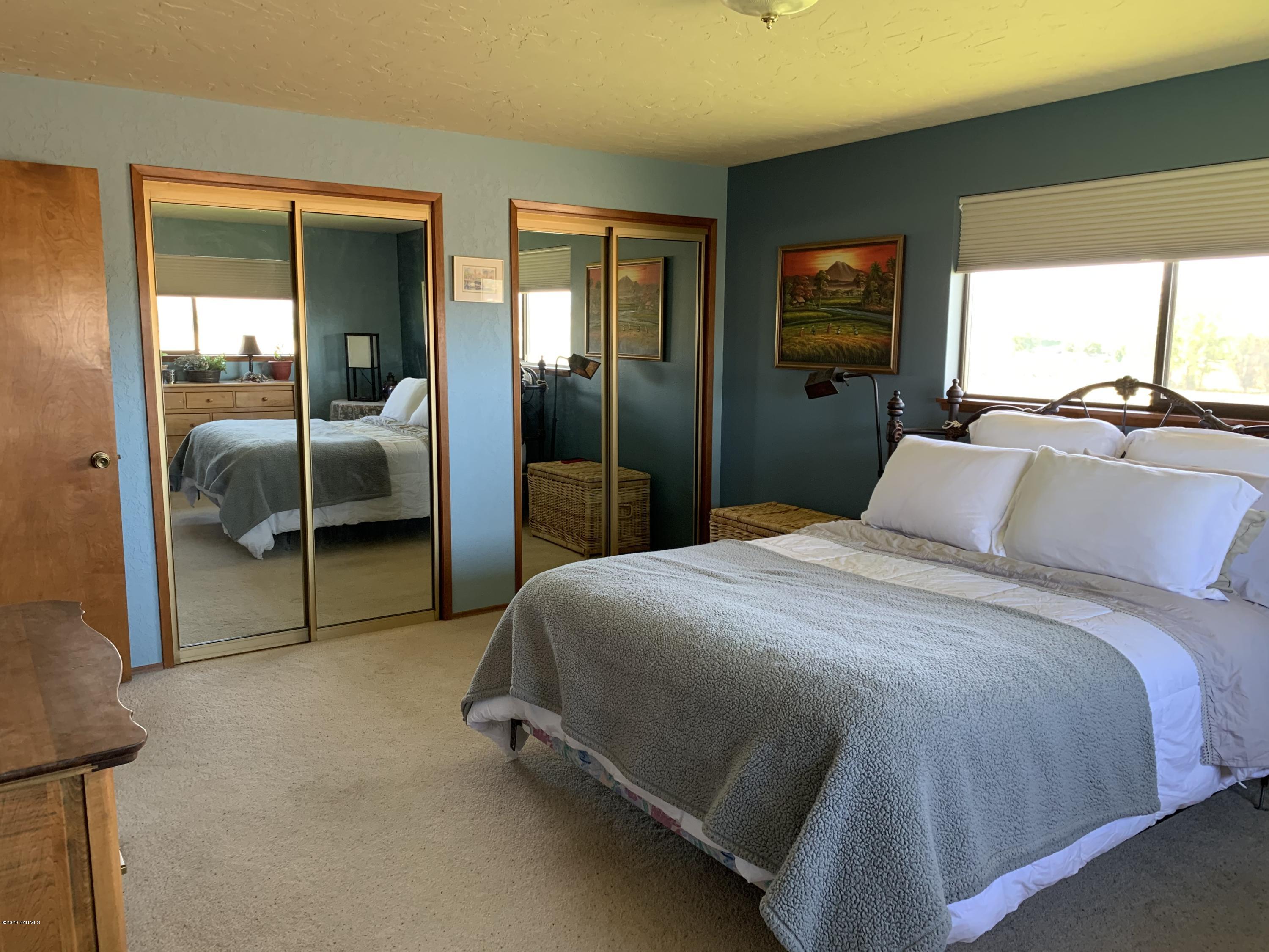 480 Pomona Heights Road Yakima, WA 98901 - Photo 10 of 39 a bedroom with a bed and large mirror next to a window