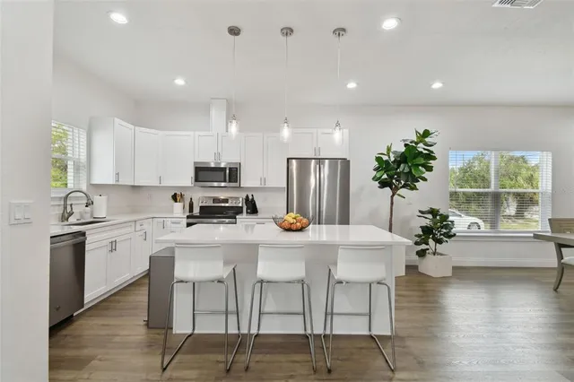a kitchen with stainless steel appliances a dining table chairs stove and refrigerator