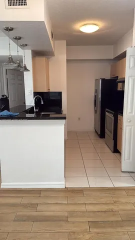 a view of a kitchen with kitchen island a sink wooden floor and electronic appliances
