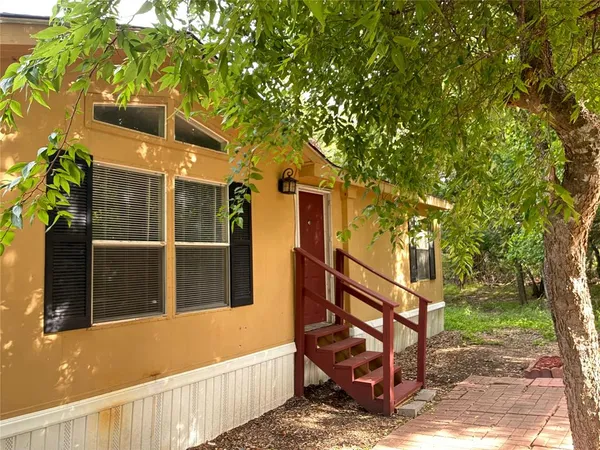 a view of a house with a large tree and wooden fence