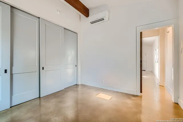 a view of a hallway with wooden floor and a bathroom