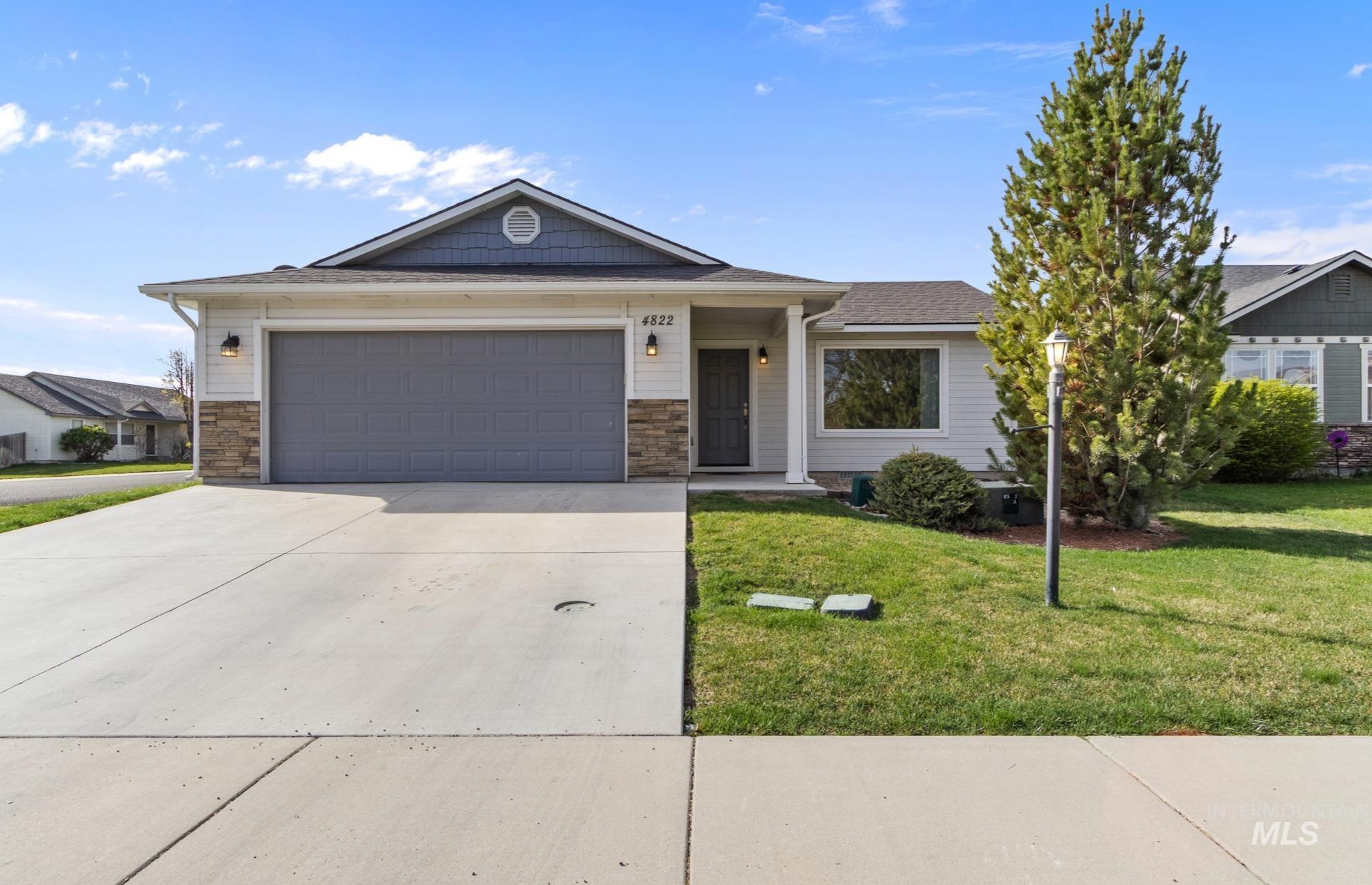 Ranch-style home with a garage, driveway, a front yard, and stone siding