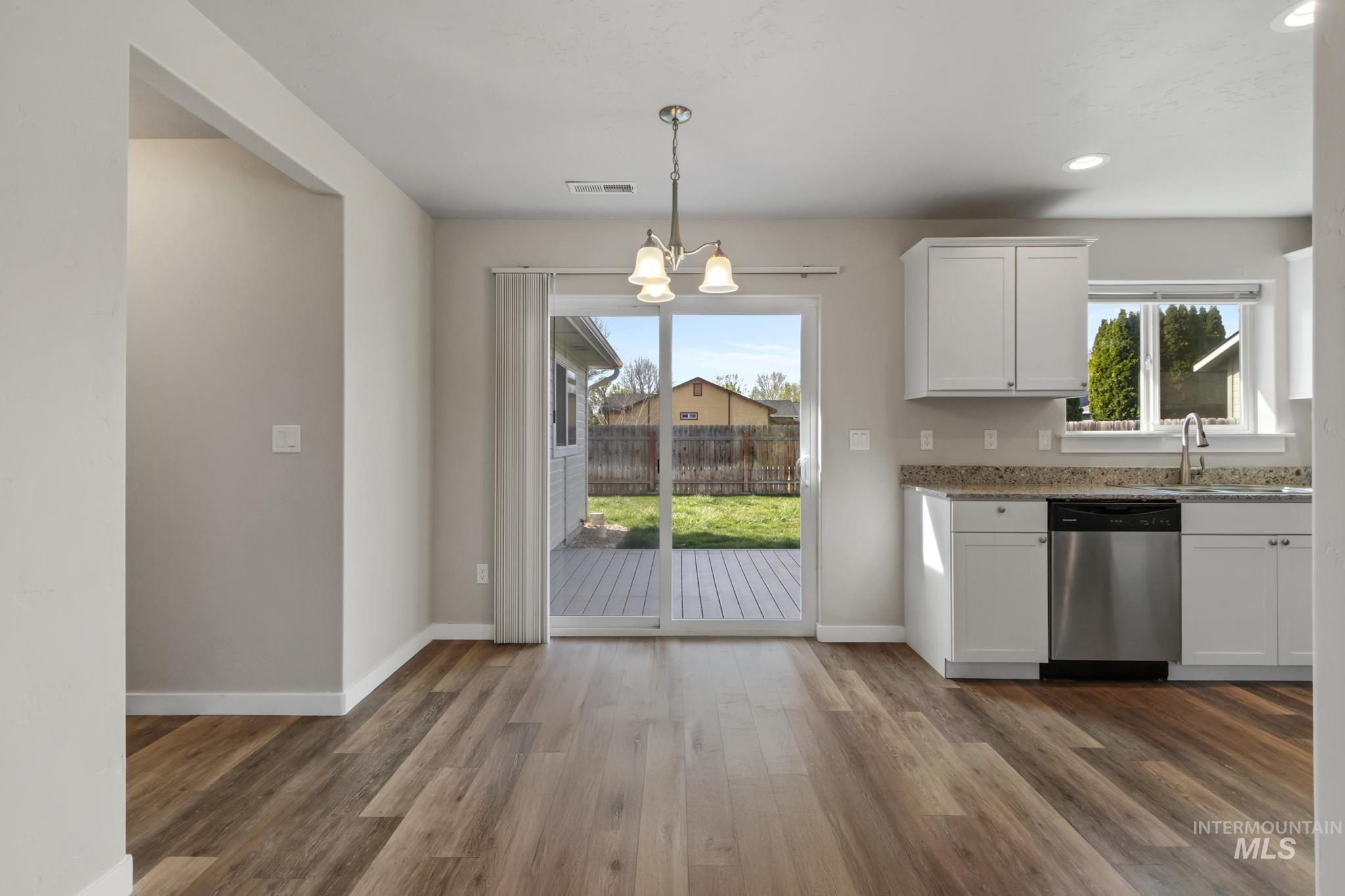 4822 Charme Street Caldwell, ID 83607 - Photo 9 of 22 Kitchen featuring suspended lighting, white cabinetry, dark wood-style floors, and dishwasher