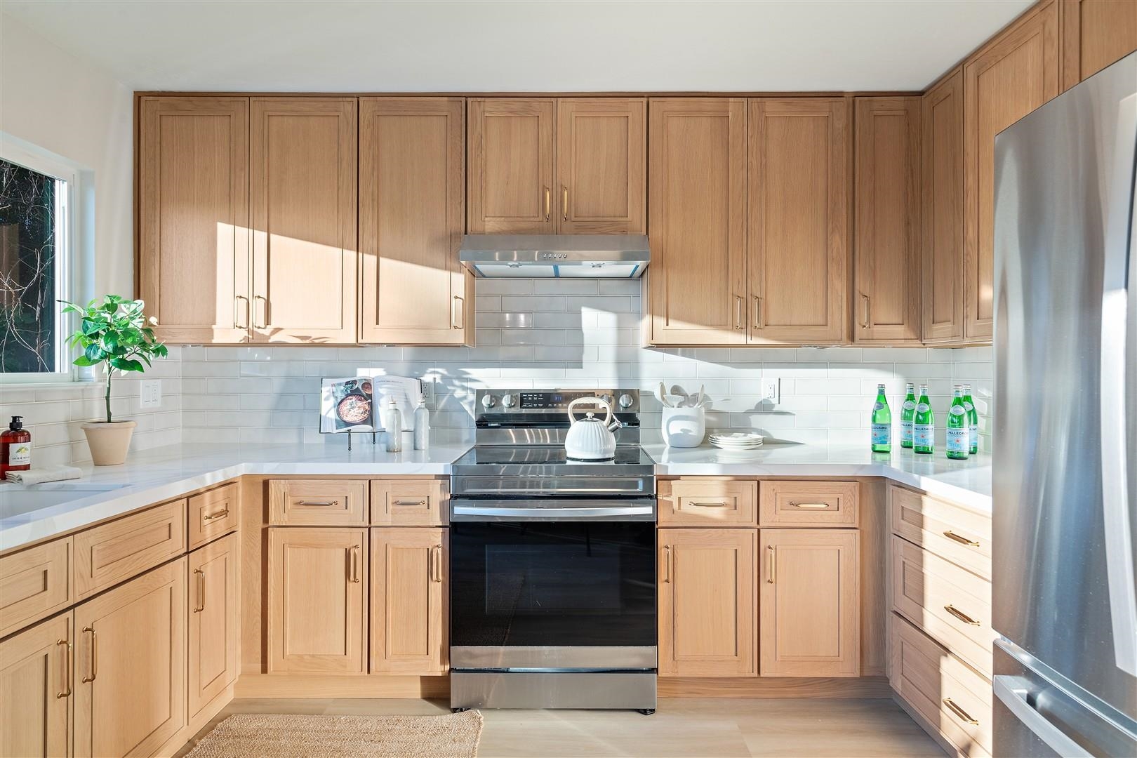 2973 Ralston Way Hayward, CA 94541 - Photo 14 of 55 Kitchen with appliances with stainless steel finishes, under cabinet range hood, light stone counters, and decorative backsplash